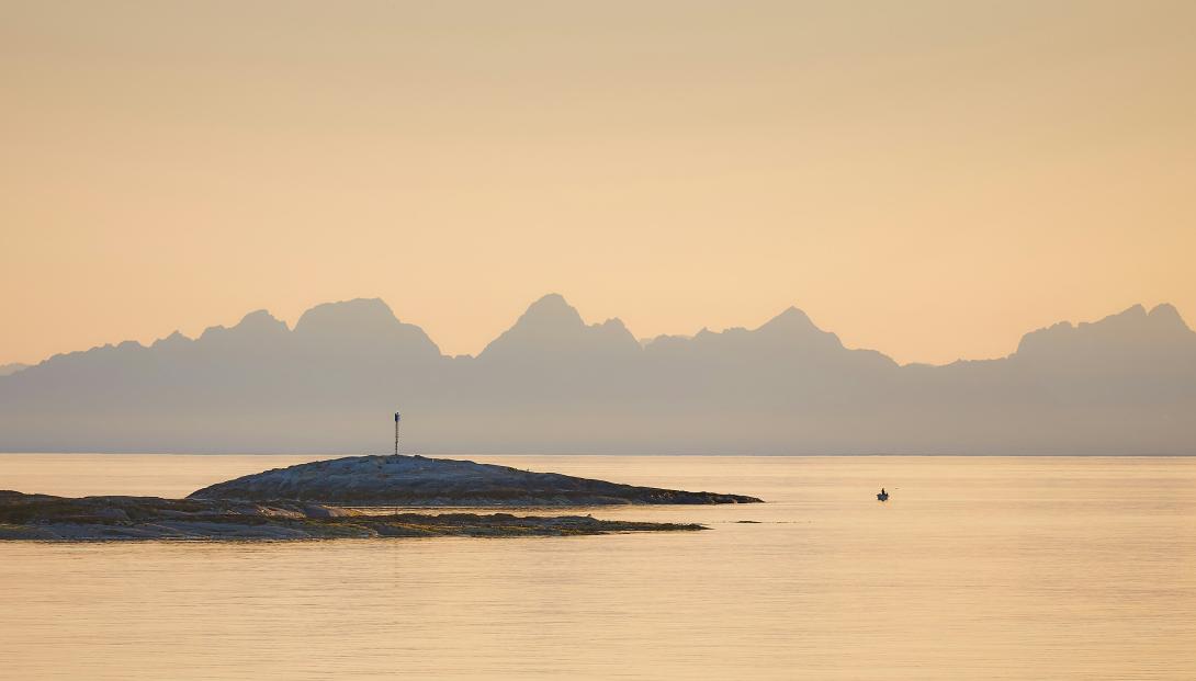 skjær i sjøen med fjell i bakgrunnen